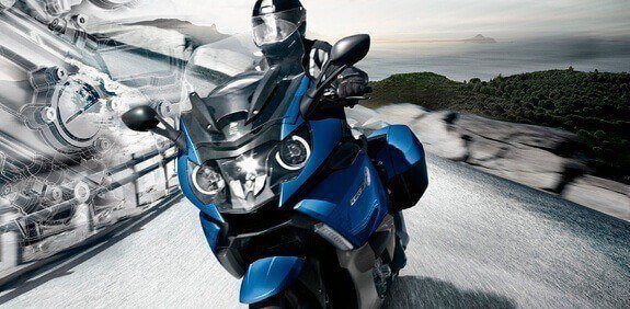 Blue touring motorcycle driving down a road